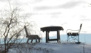 Dve lavičky a stôl pokryté snehom na kopci pod oblakmi